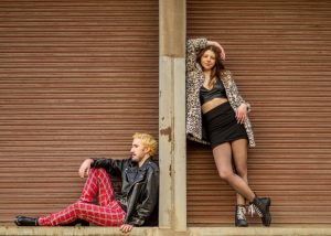 Two cast members of RENT posing against the Queens Theatre